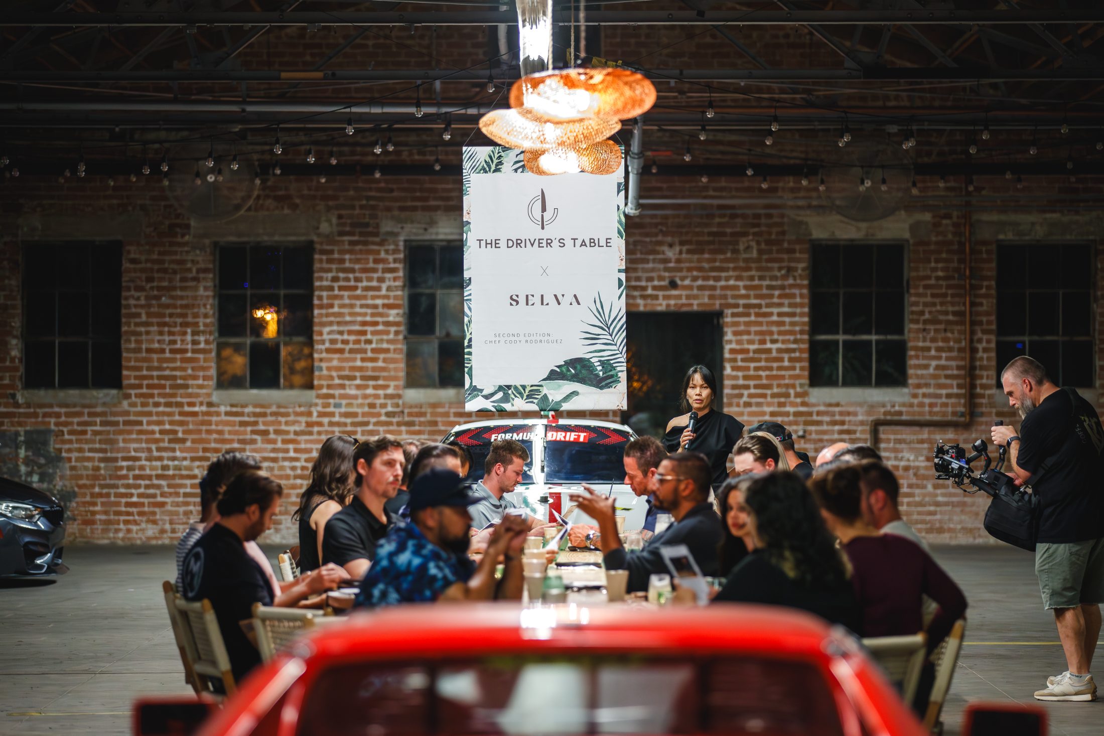 Dinner at a long table in the warehouse, low warm light
