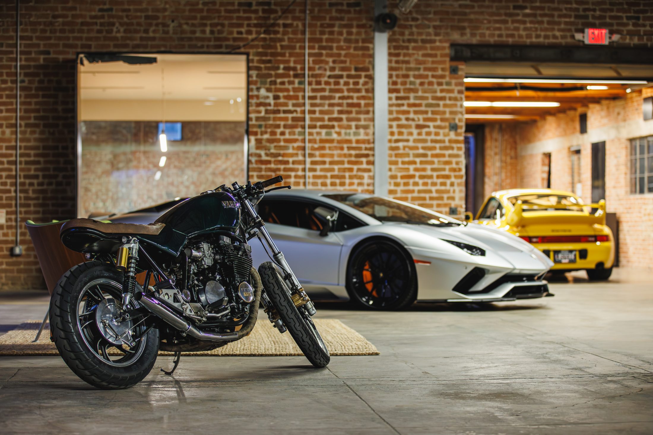 Motorcycle and cars stored under warm warehouse light