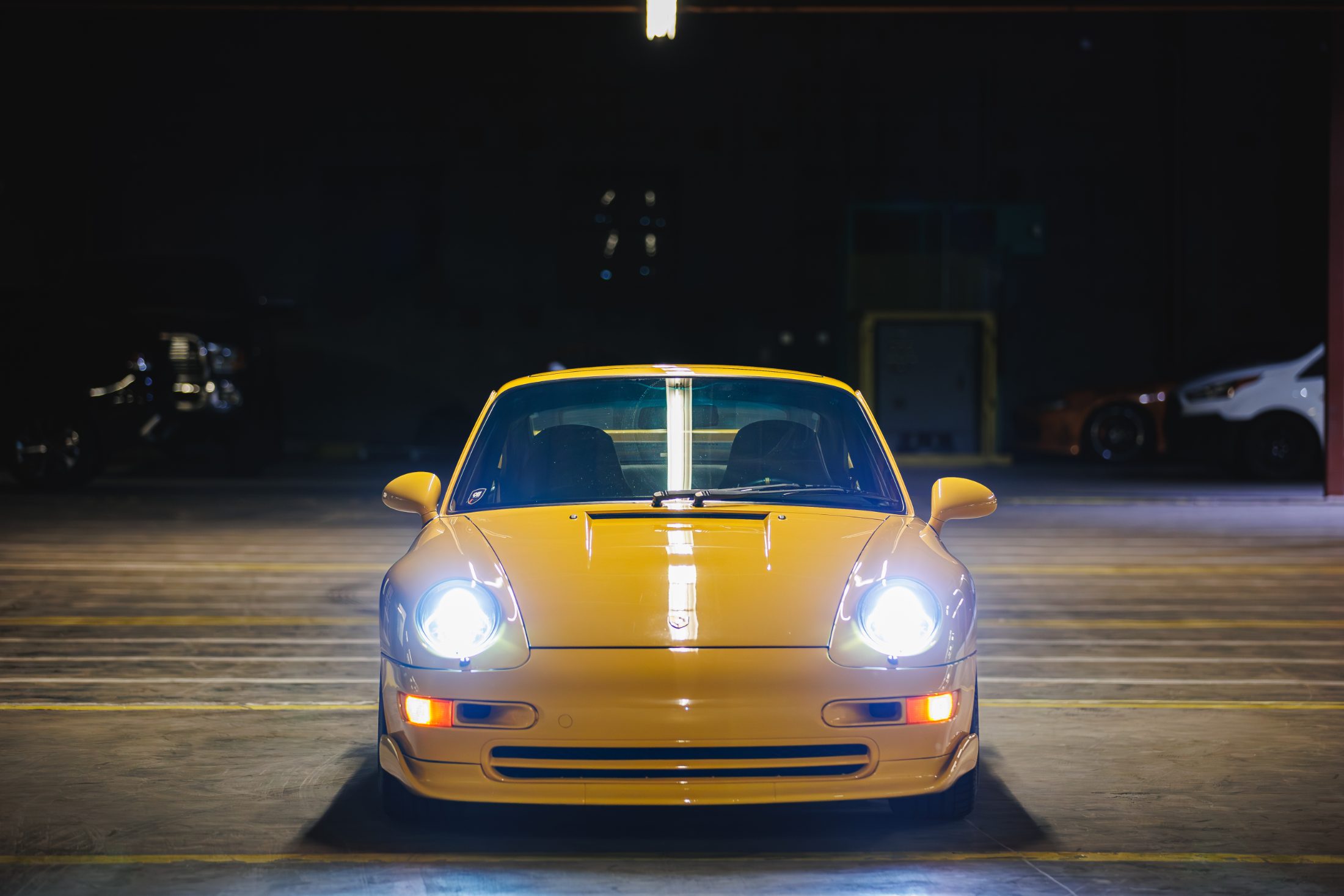 A single car on the warehouse floor under one light